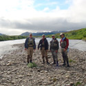four anglers hike a creek